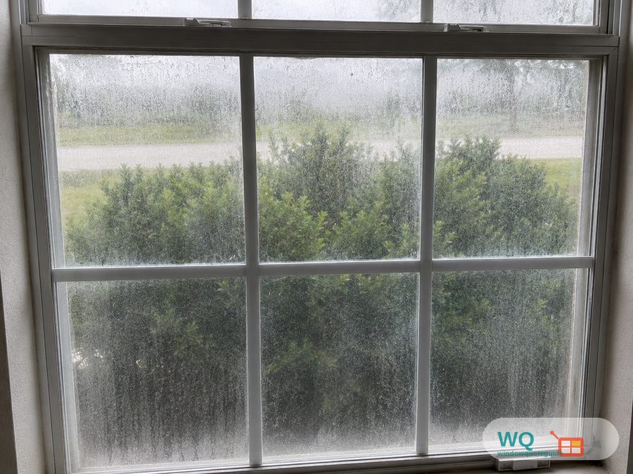 A double-pane window fogged with condensation trapped between the glass, blurring the view outside